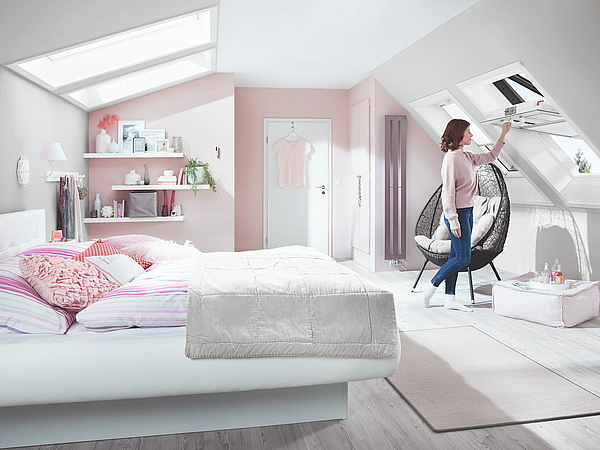 Fermeture de fenêtre de toit par une dame dans une chambre à coucher